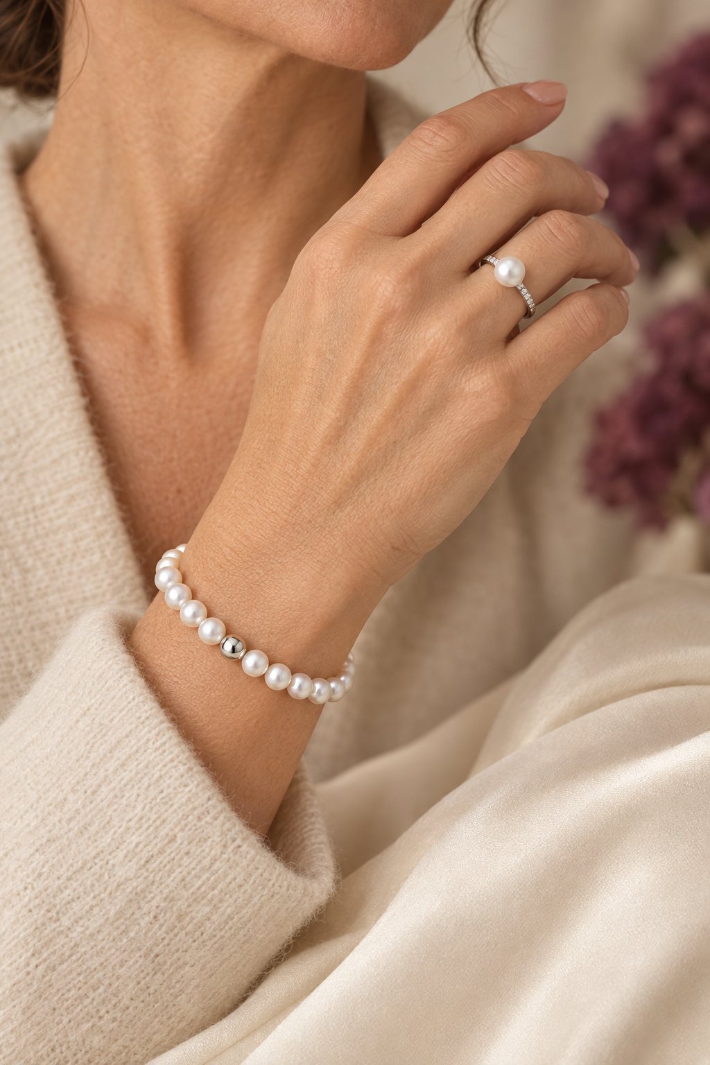 Hand mit Perlenarmband und Perlenring